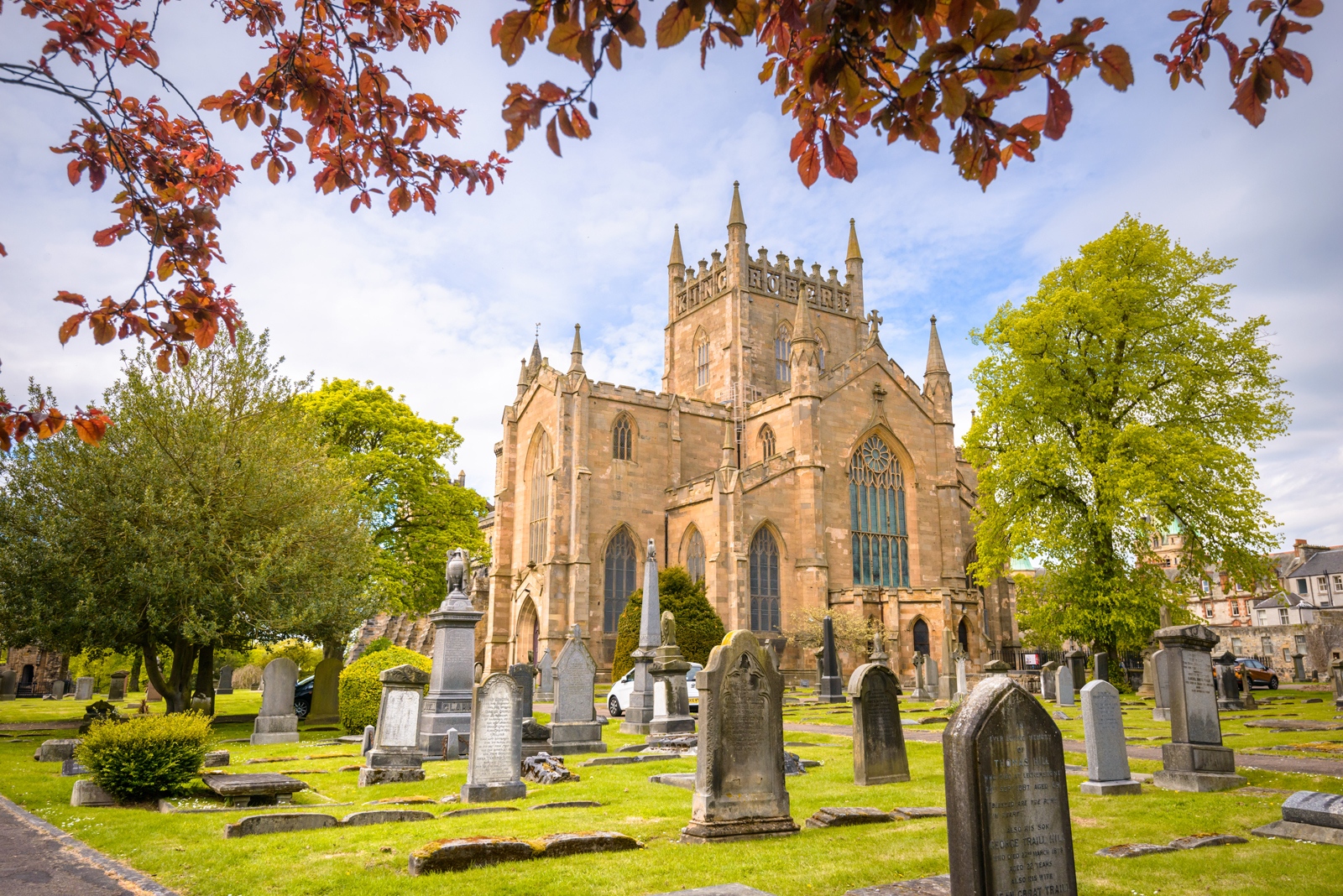 A picture of Dunfermline Abbey, pictured from the graveyard, surrounded by trees